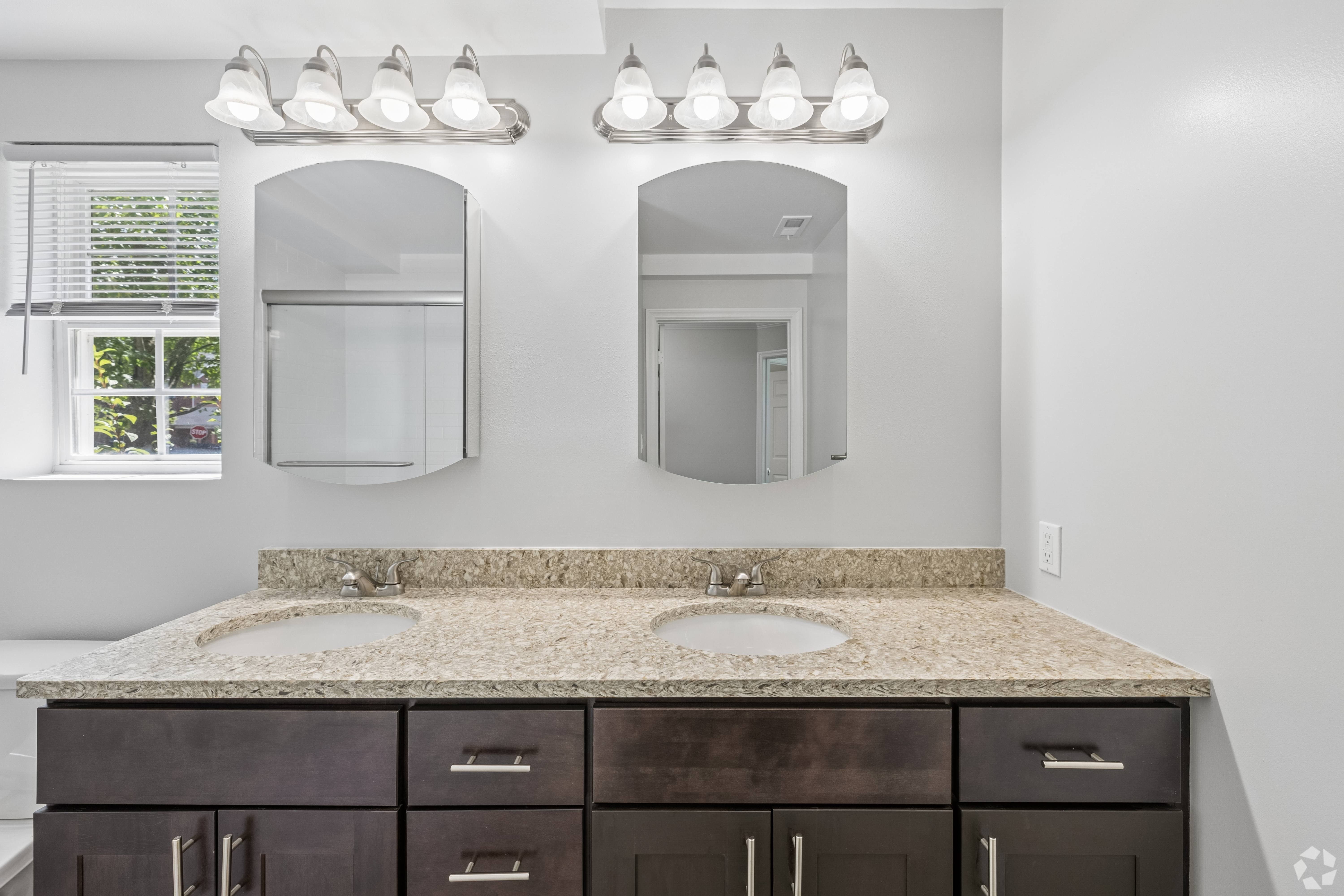 A bathroom with a granite countertop and two sinks.